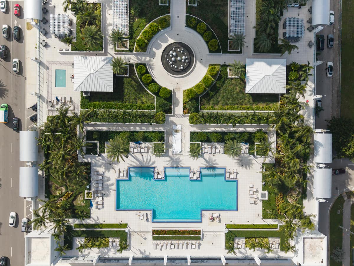 Overhead drone view of a landscaped resort-style pool deck and courtyard